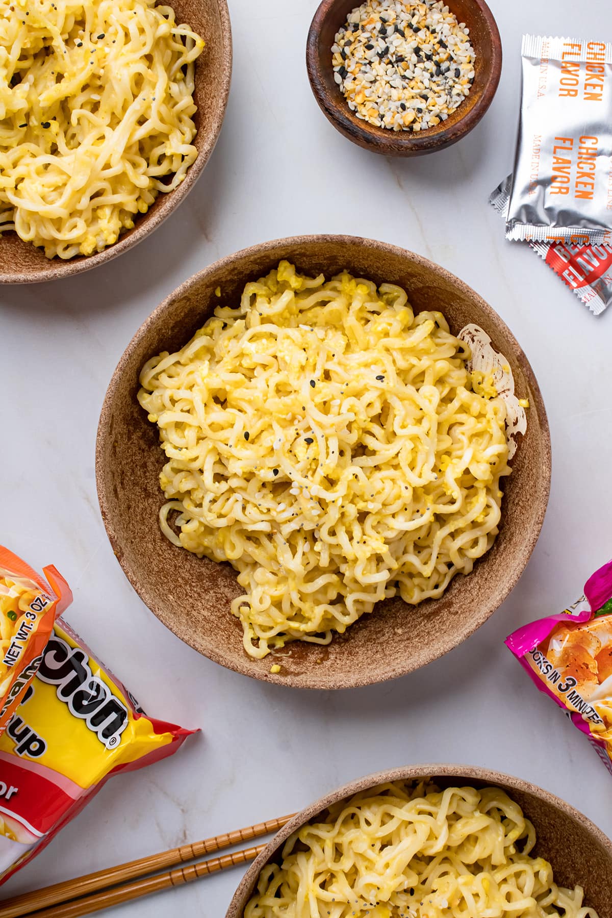 Overhead view of Kylie Jenner's Ramen noodles in a bowl surrounded by more ramen noodles, spices, and chopsticks.