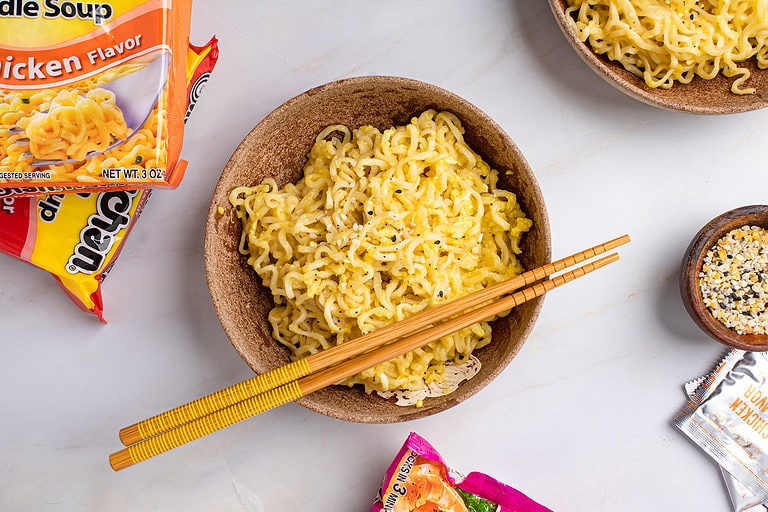 Overhead view of prepared ramen noodles in a light brown serving bowl with 2 wooden chopsticks laying across the top of the bowl.