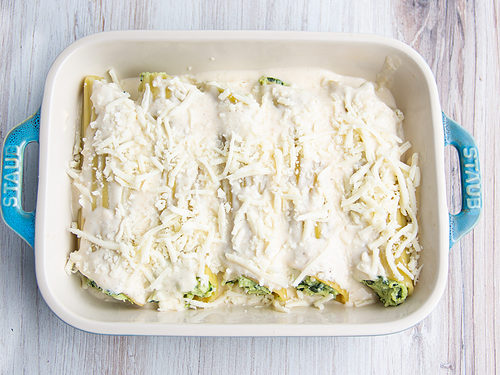 Chicken and spinach manicotti topped with mozzarella in a baking dish.