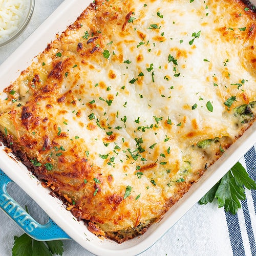 Overhead view of a dish of cheesy chicken and spinach manicotti in a baking dish.