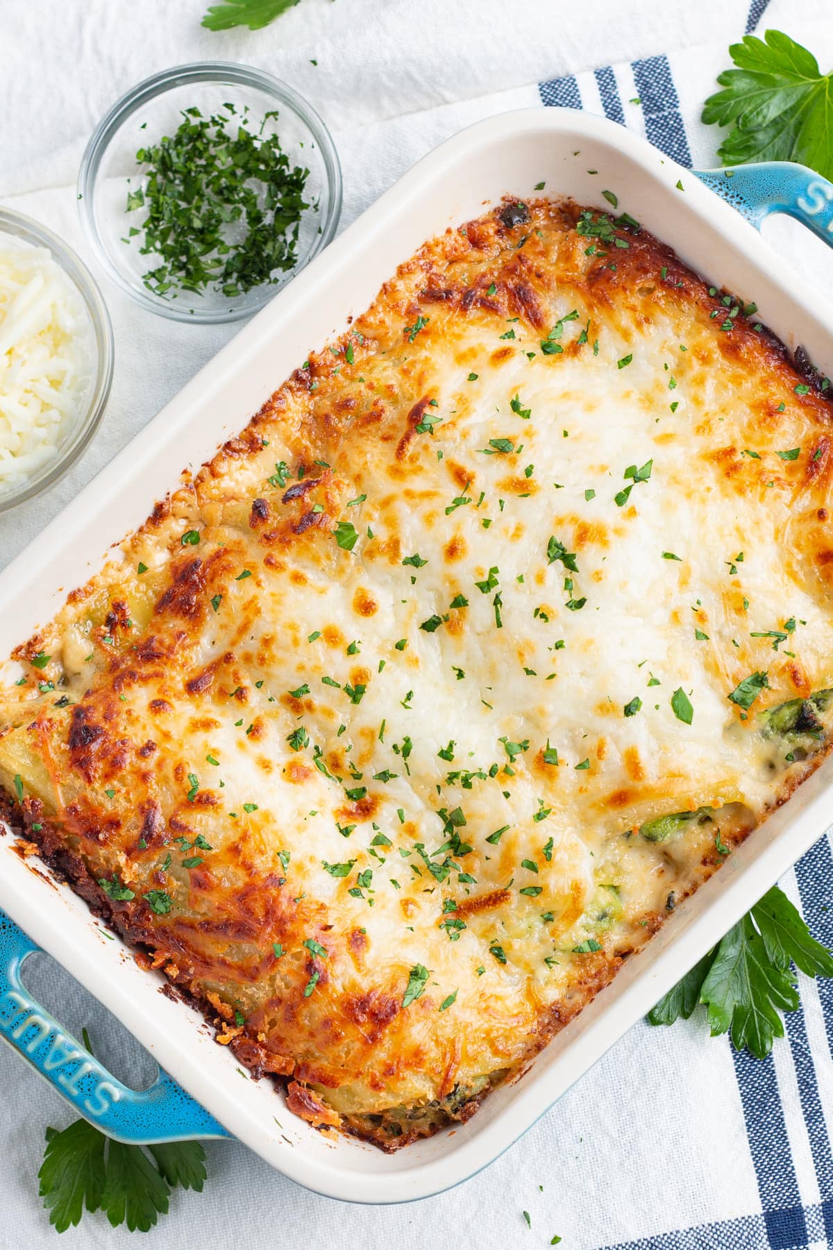 Overhead view of a dish of cheesy chicken and spinach manicotti in a baking dish.