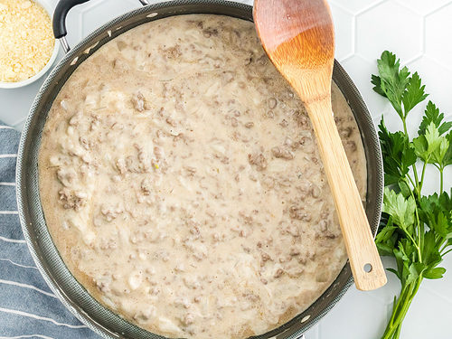 Ground beef, onions, garlic, and alfredo sauce in a large skillet.