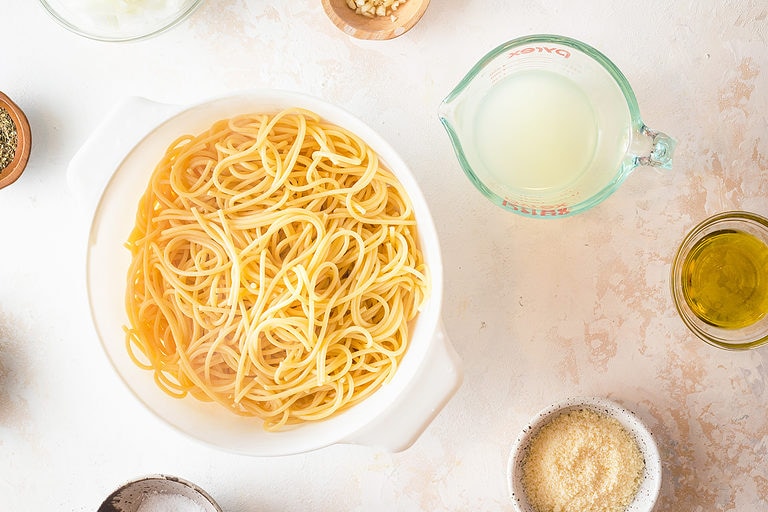 Overhead view of ingredients for pasta napoletana in bowls and a colander.