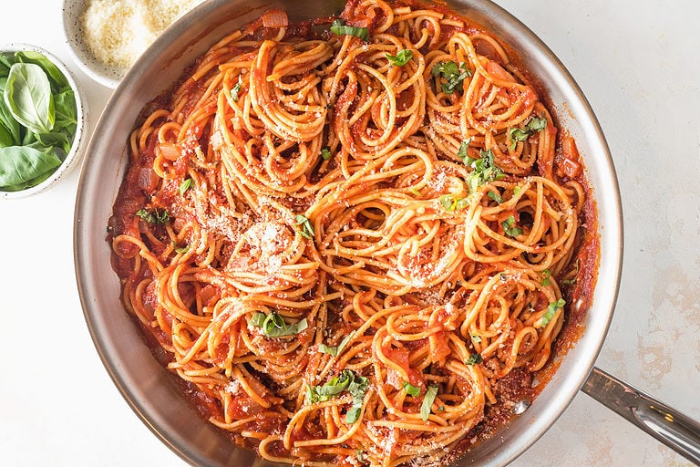 Overhead view of prepared pasta napoletana in a large silver skillet.