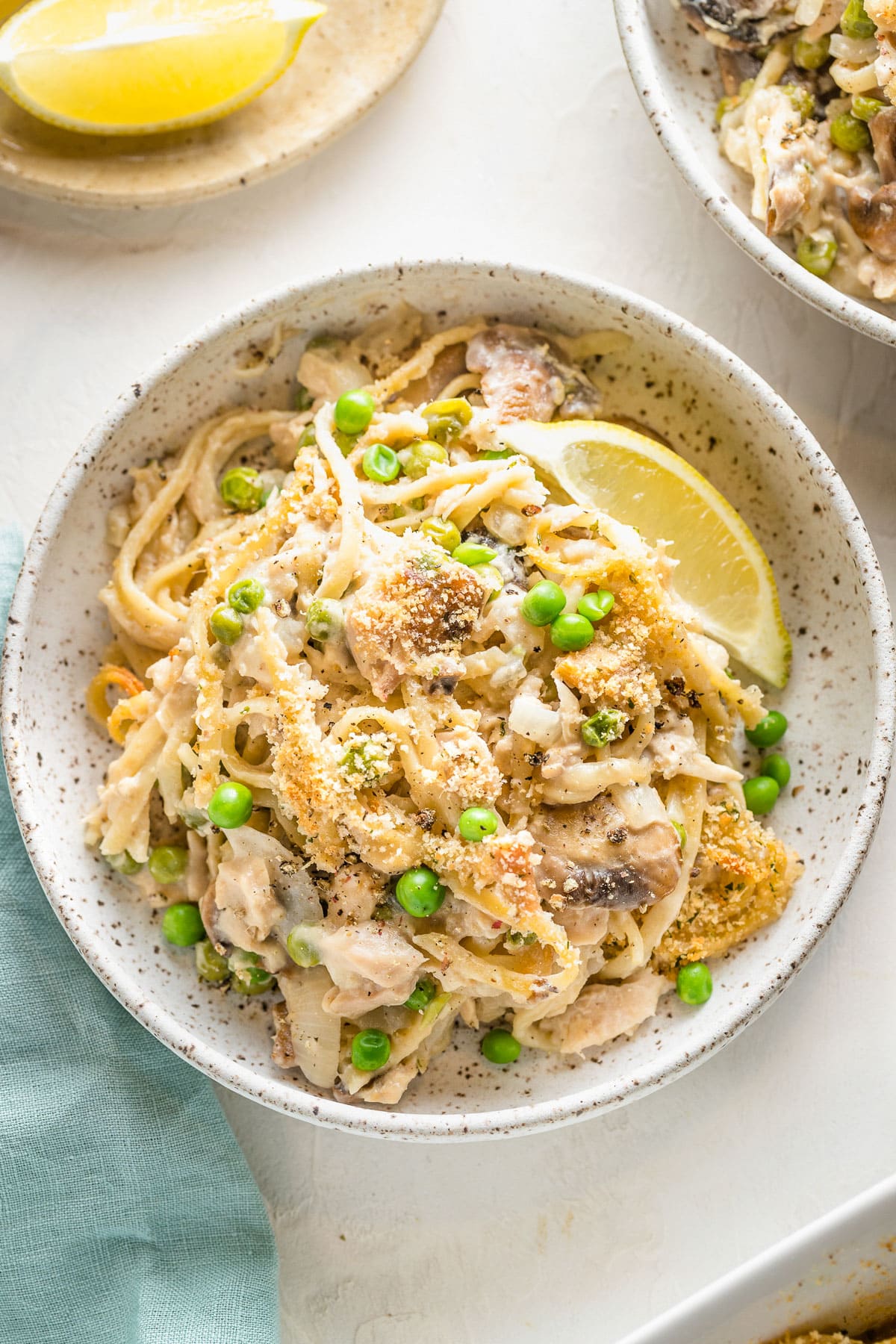 Close up of a bowl of tuna tetrazzini with a lemon wedge.