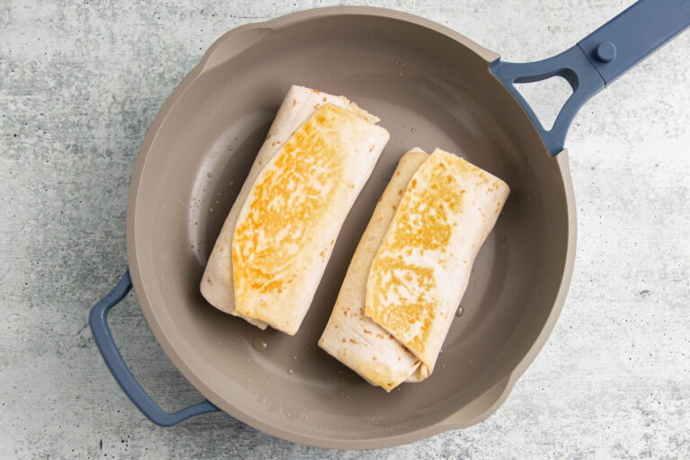 Two rolled burritos in a large skillet.