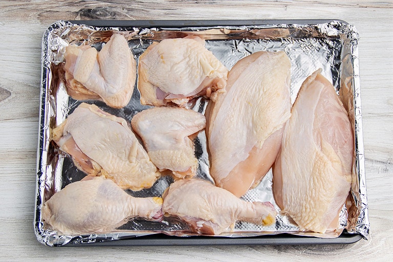 Uncooked cuts of chicken on a baking sheet lined with aluminum foil.