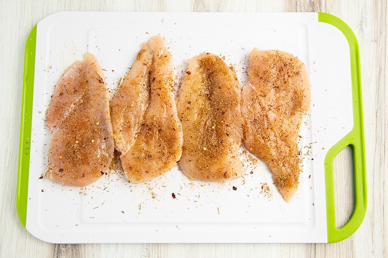 Seasoned jerk chicken on a cutting board.