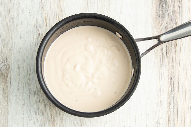 Alfredo sauce in small saucepan.