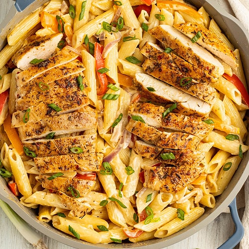 Overhead view of jerk chicken alfredo in a large skillet.