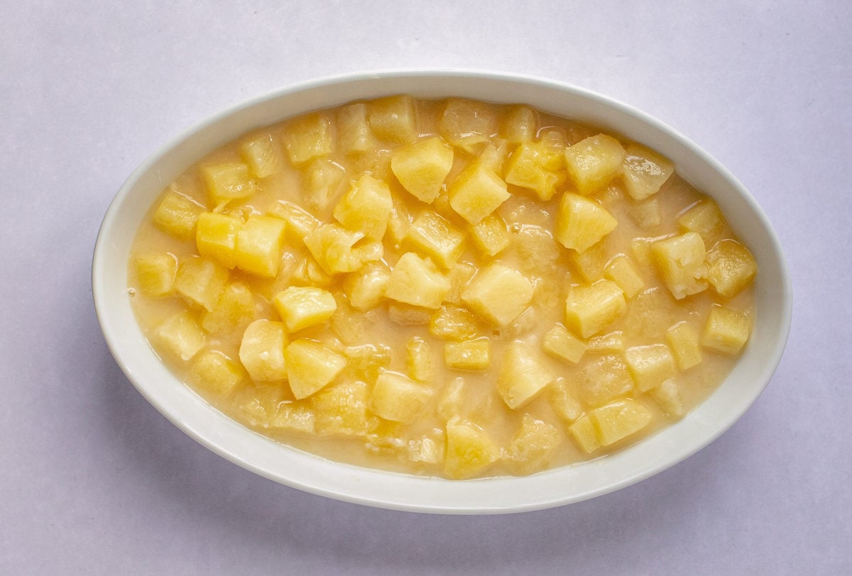 Pineapple casserole filling in an oval, white casserole dish.