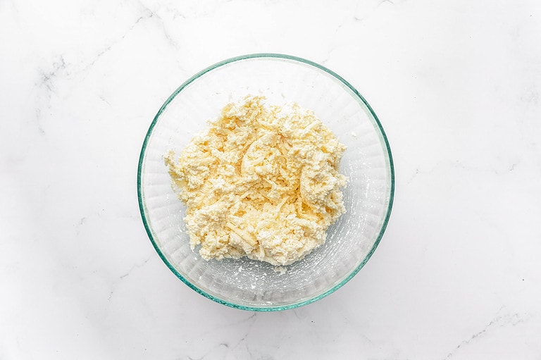 Ricotta, mozzarella, and parmesan mixture in a glass mixing bowl.