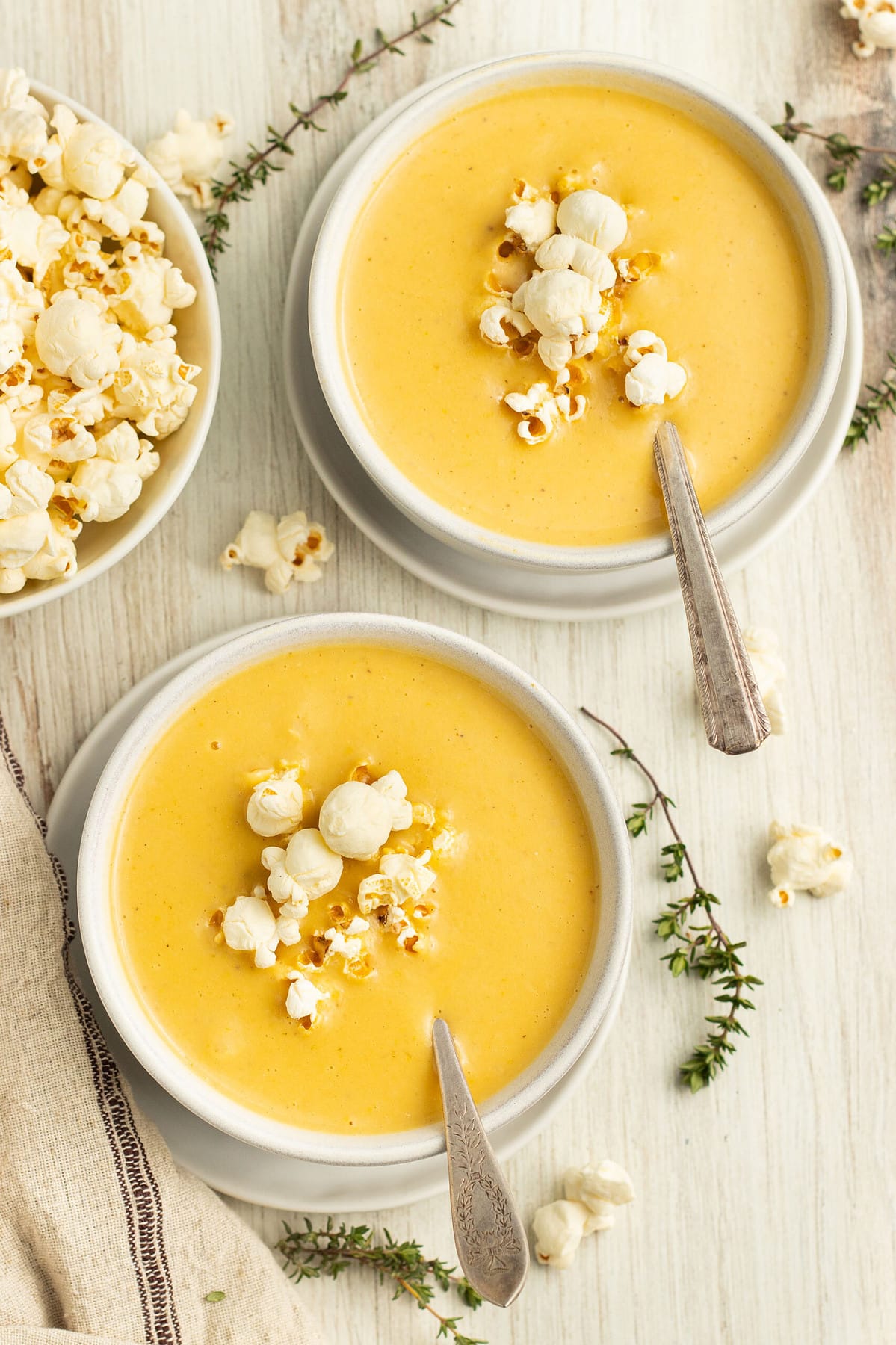 Overhead image of two bowls of popcorn soup with another bowl of popcorn off to one side.