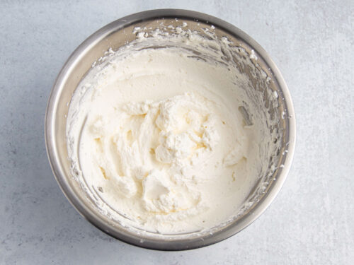Homemade whipped cream in a large sliver mixing bowl.