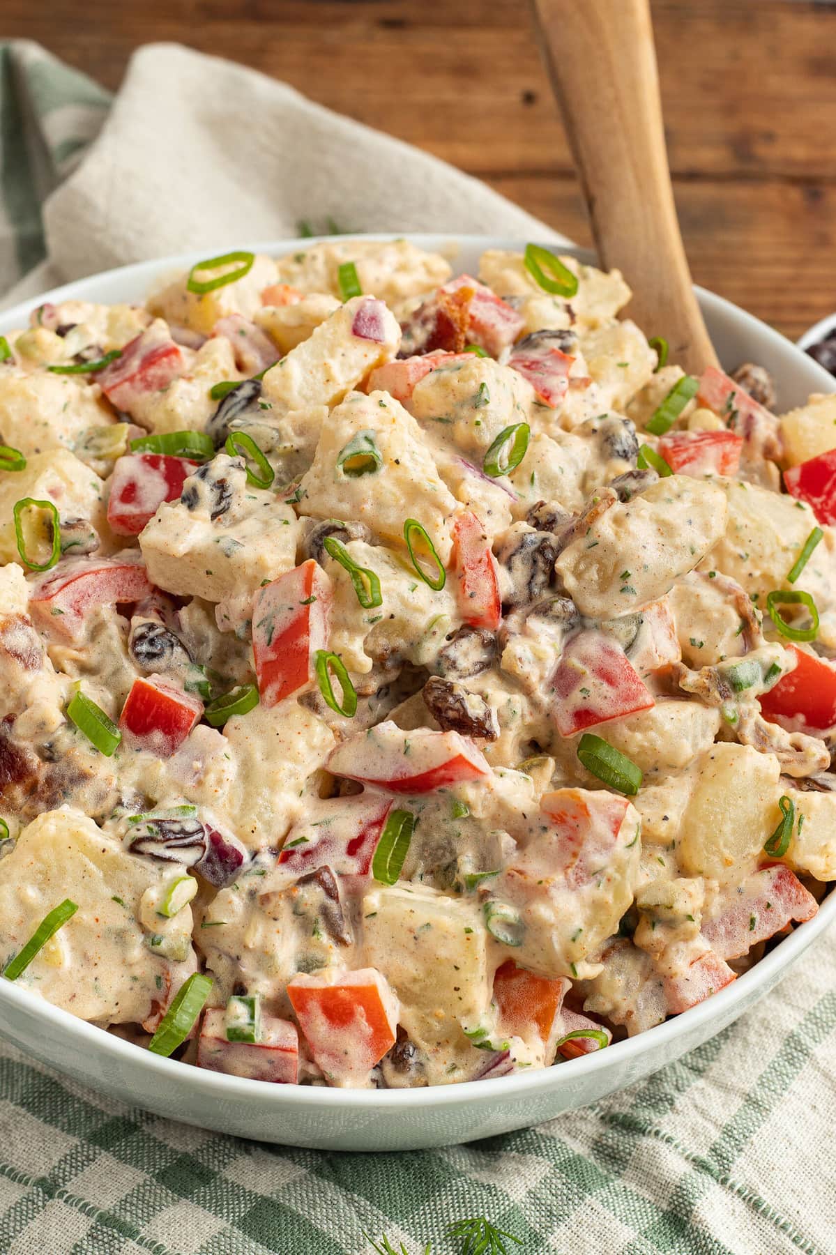 Potato salad with raisins, red onions, and red bell pepper in a large bowl.