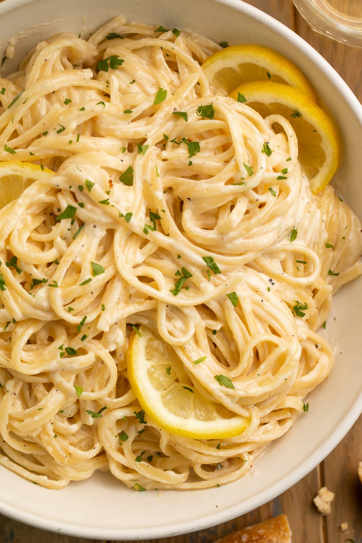 A bowl of lemon pepper pasta made with spaghetti noodles and garnished with lemon wedges.