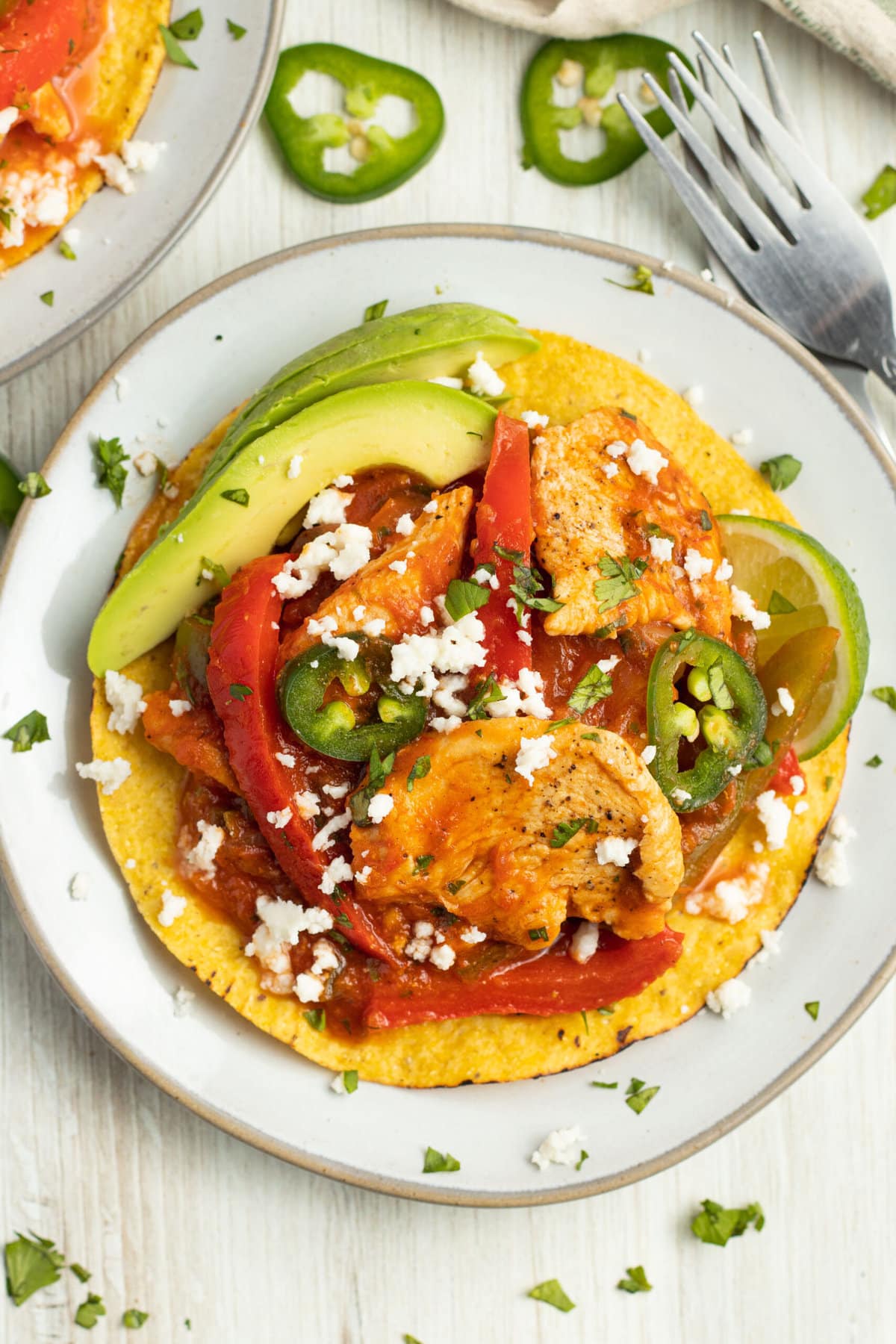 Chicken ranchero on a tostada with queso fresco, avocado, peppers, onions, and jalapeno.
