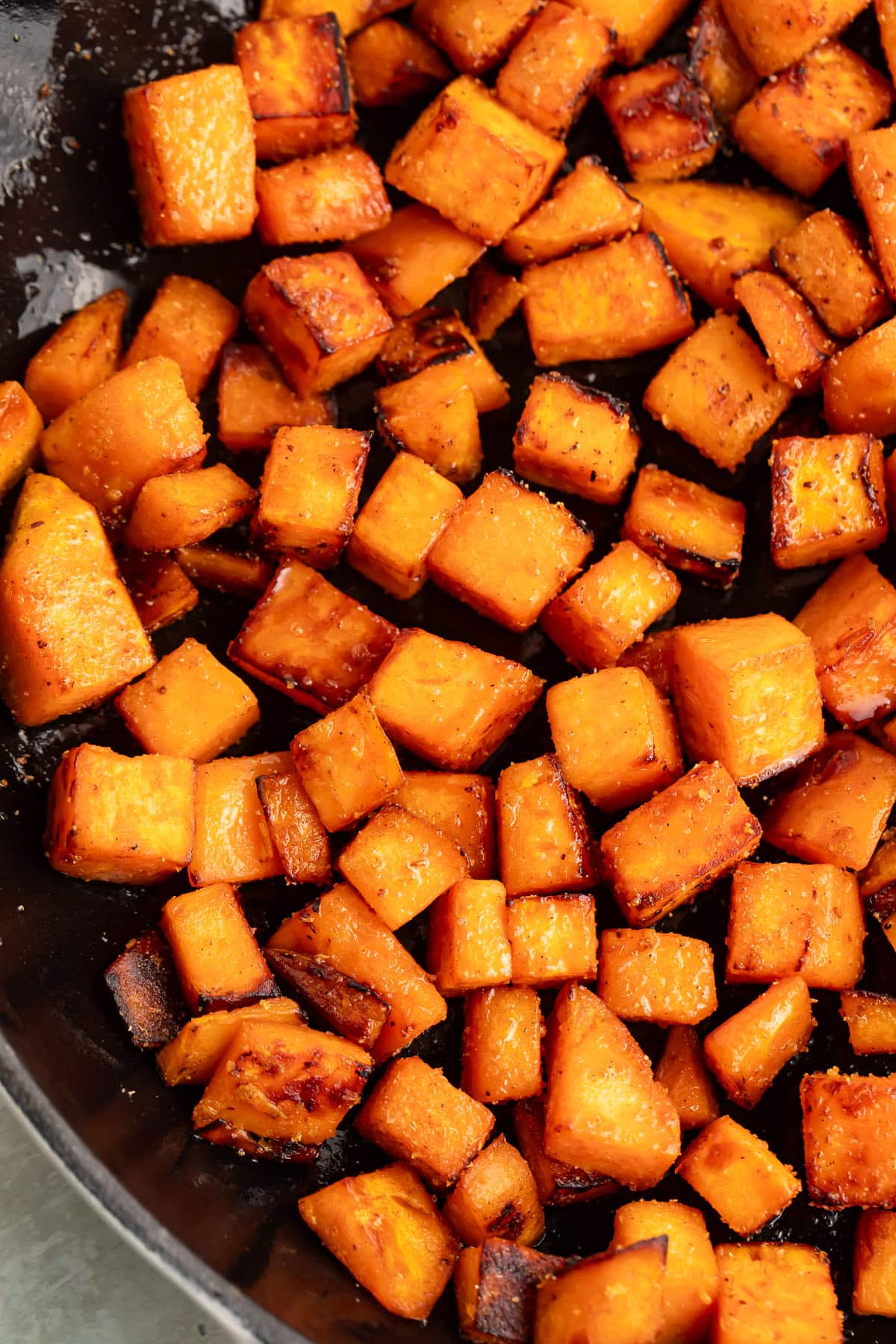 Sautéed sweet potatoes, cubed, in a large cast-iron skillet.