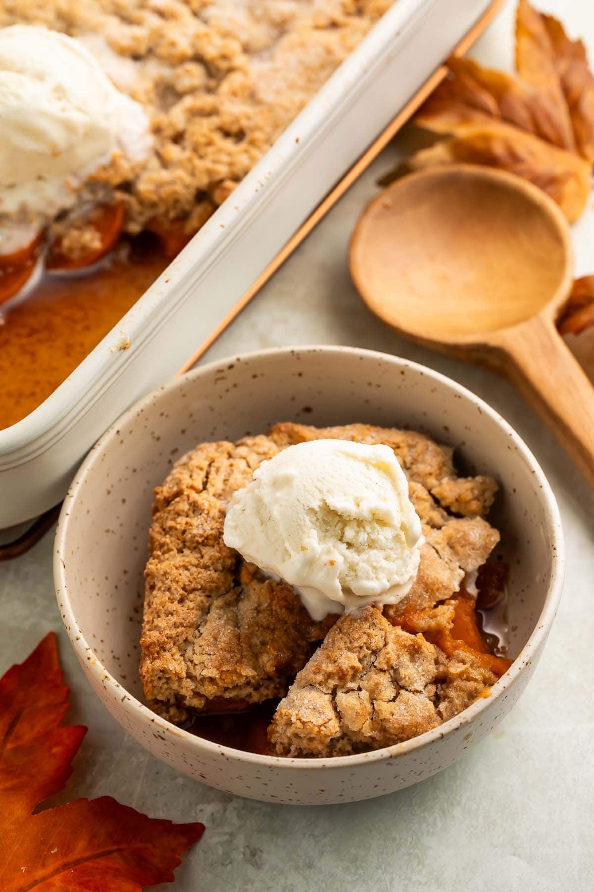 A bowl of sweet potato cobbler topped with a scoop of vanilla ice cream.