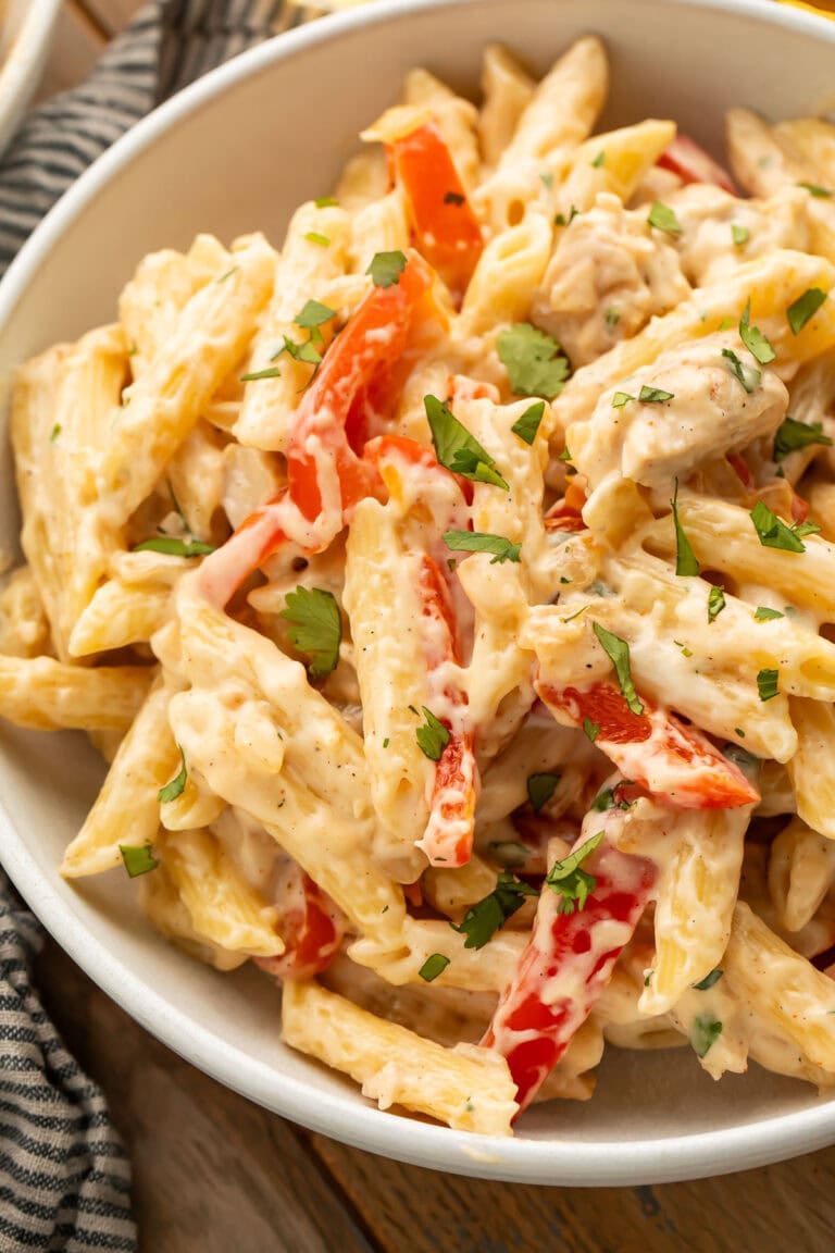 Close-up photo of a large bowl of rattlesnake pasta with penne, chicken, red bell pepper, jalapeno, onion, and a cream sauce.