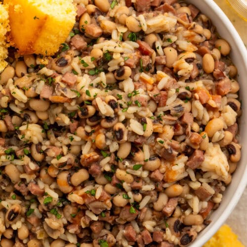 Close-up on a large bowl of black eyed peas and rice with two squares of cornbread.
