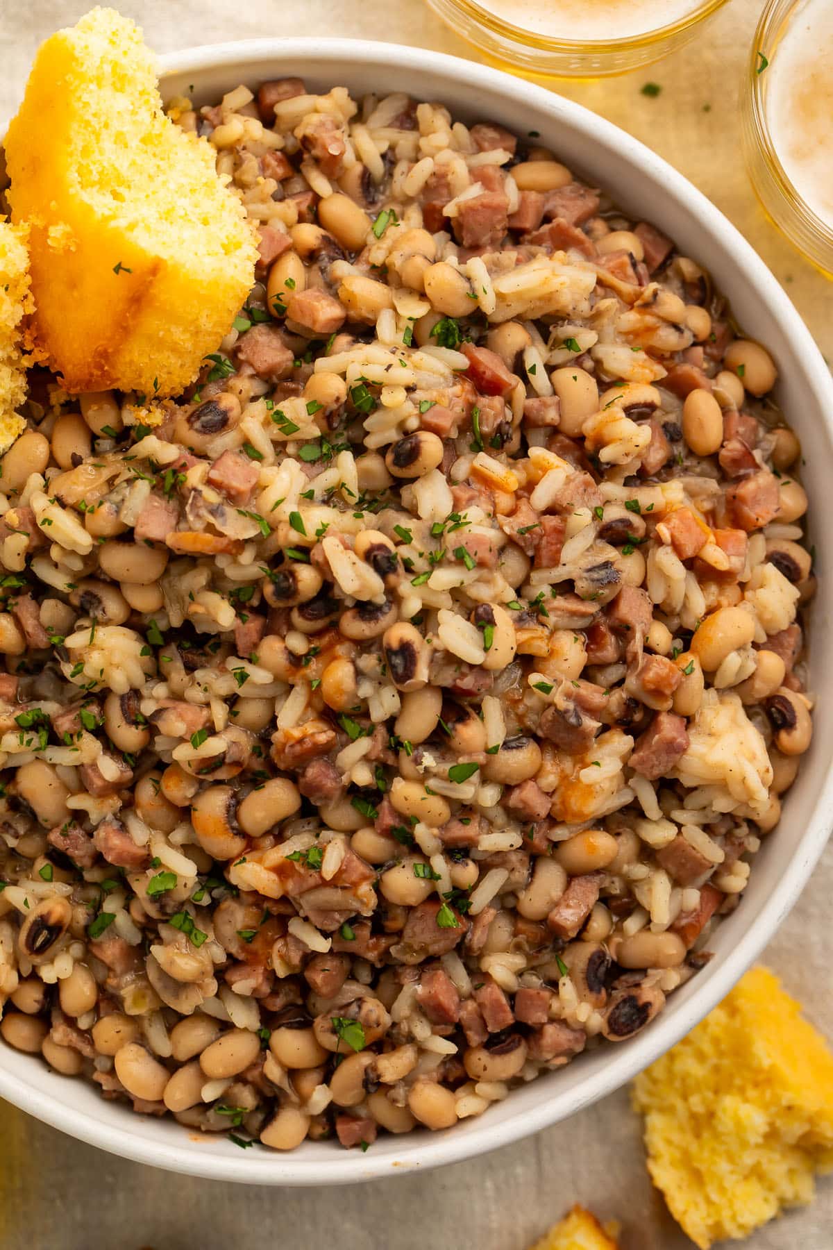 Close-up on a large bowl of black eyed peas and rice with two squares of cornbread.