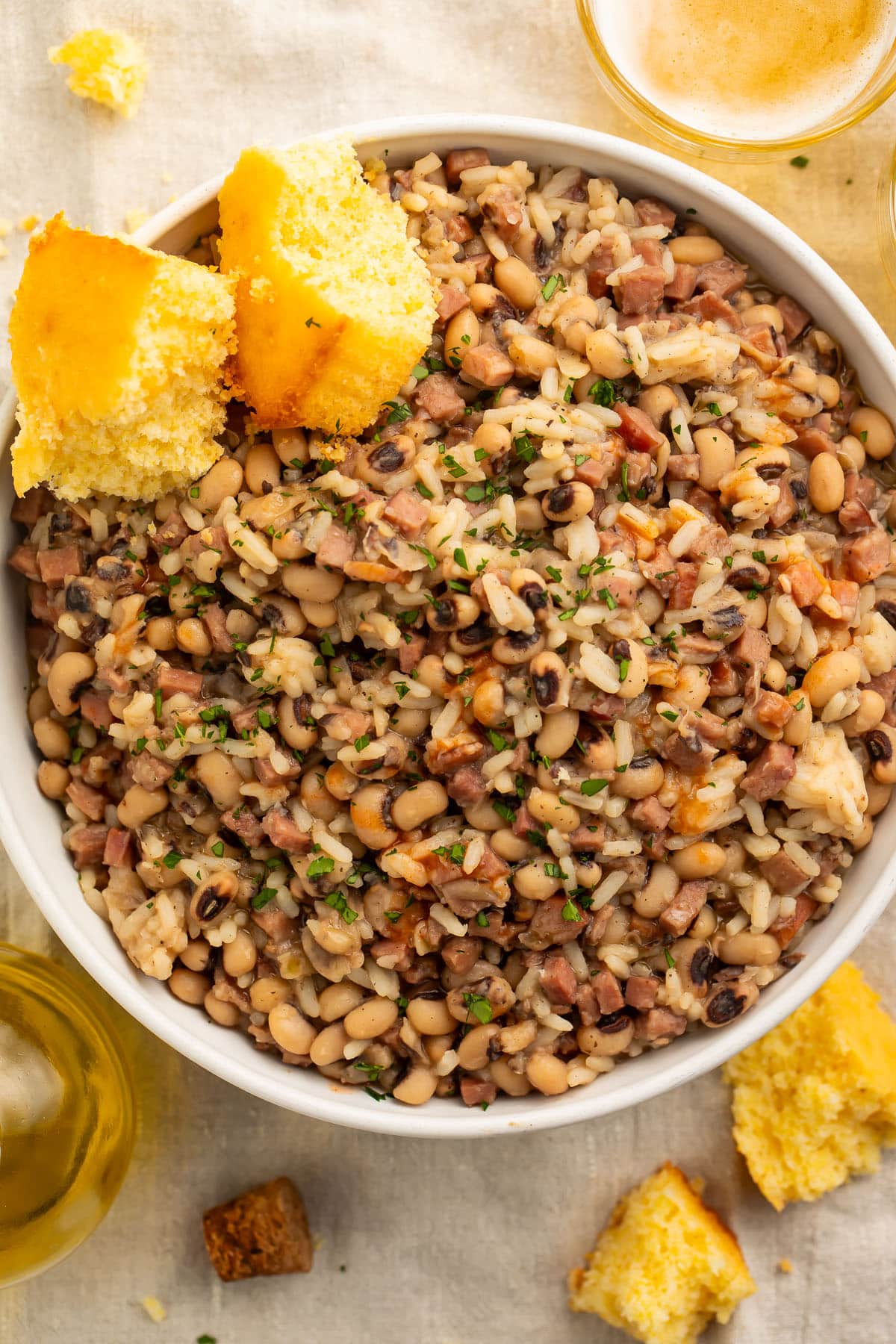 A large bowl of black eyed peas and rice with two squares of cornbread.