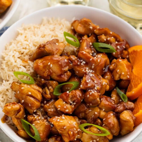 Tangerine chicken in a bowl with white rice.