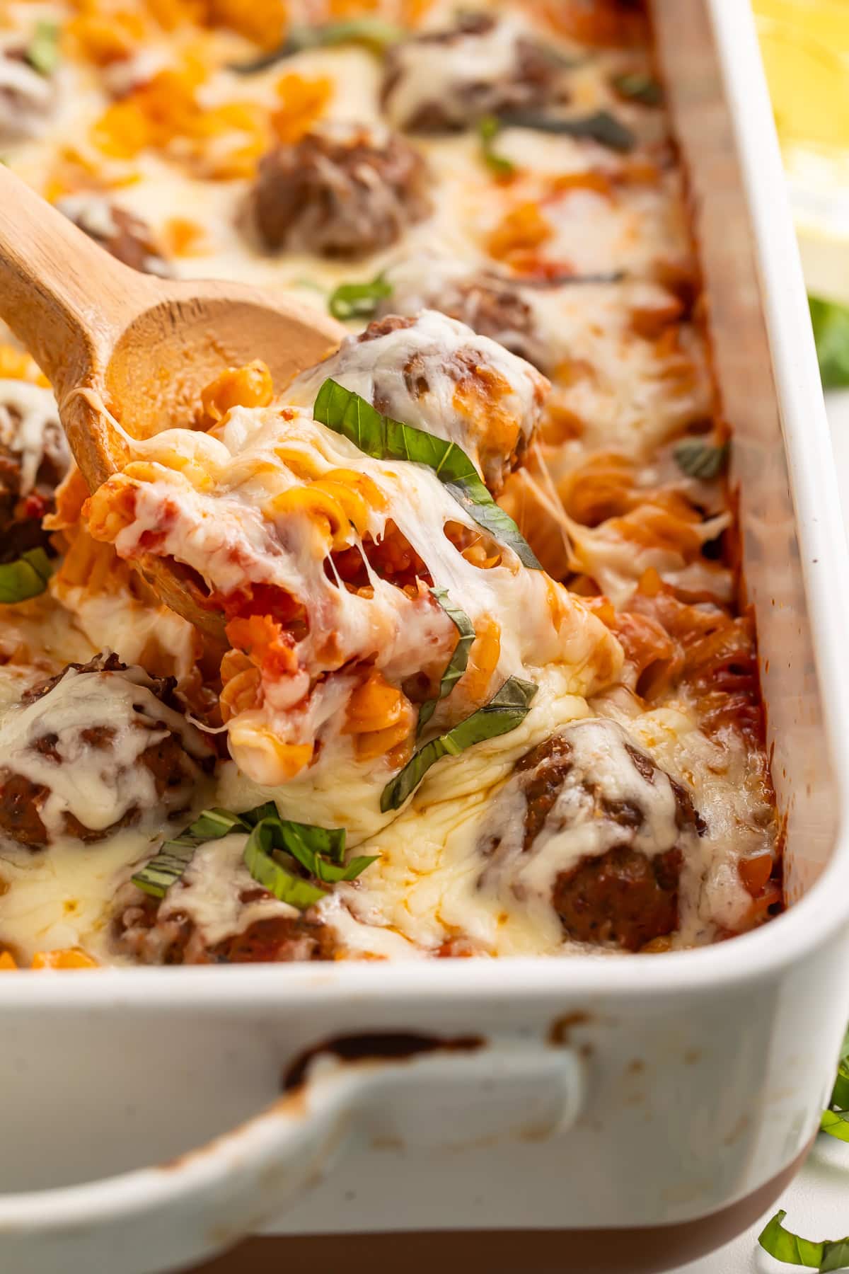 A cheesy dump and bake meatball casserole being served pictured close up.