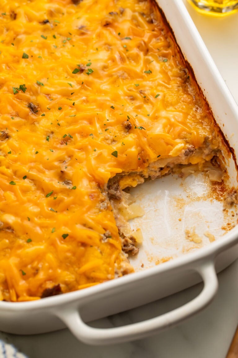 Close up of a hobo casserole baked in a white baking dish with a portion removed from the corner.