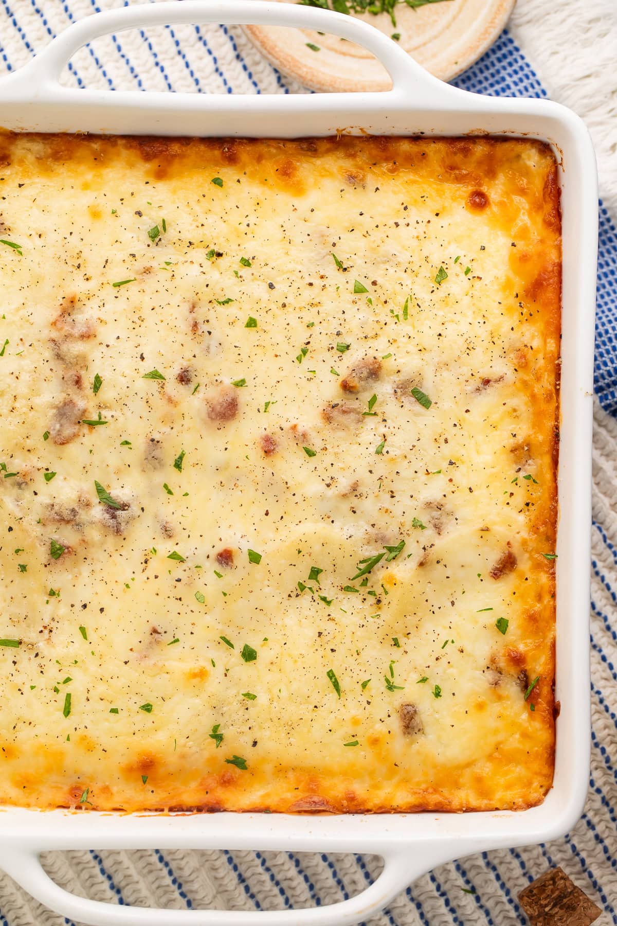Close up of a baked potato lasagna with parsley scattered on top of the melted cheese.