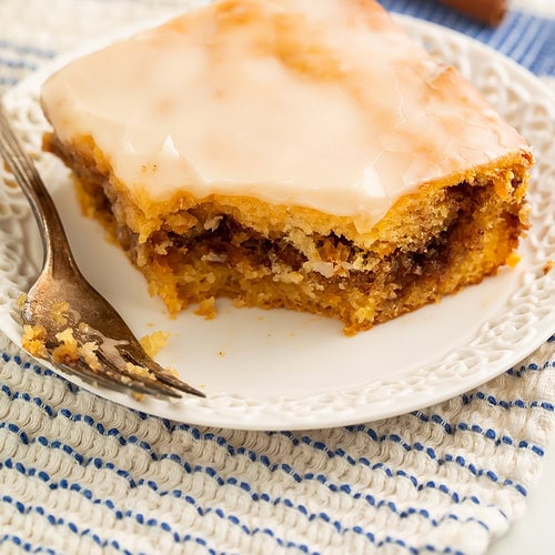 Slice of glazed honey bun cake on a plate showing the cinnamon swirl through the middle.