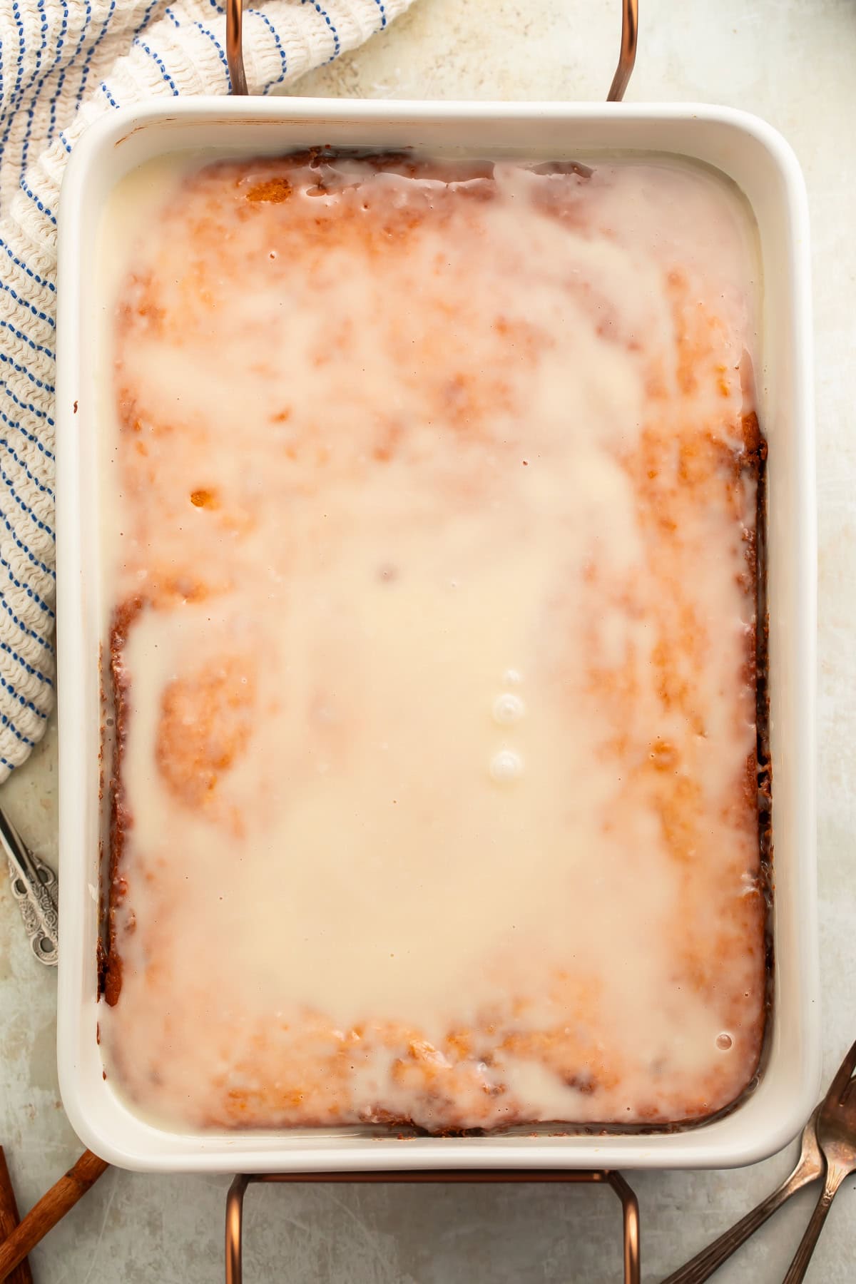 Overhead image of a honey bun cake topped with glaze in the baking dish.