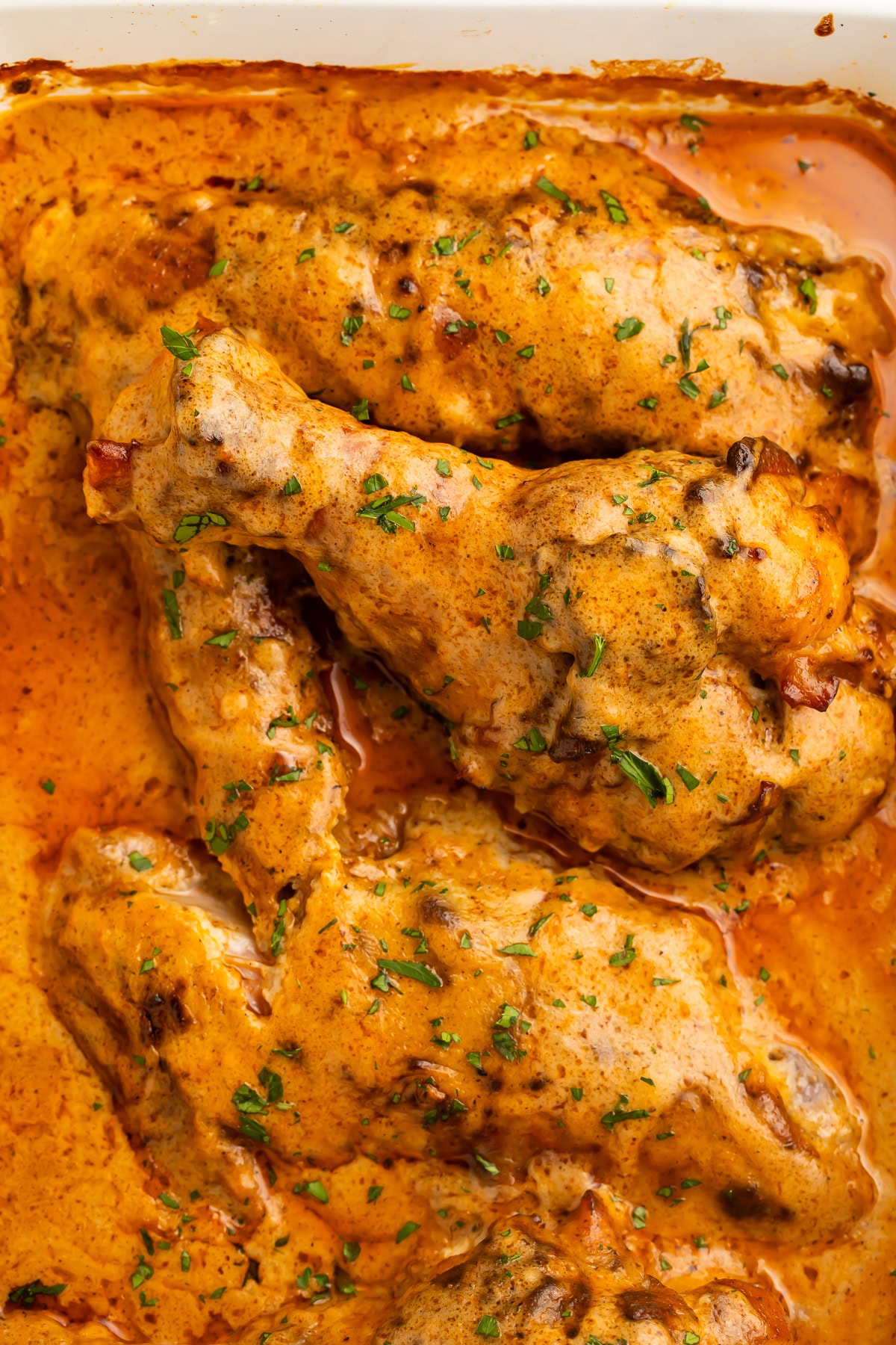 Close up of smothered turkey wings scattered with chopped parsley.