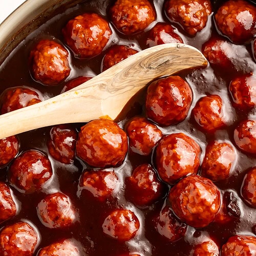 Close up of a pan of sticky glazed cranberry barbecue meatballs.