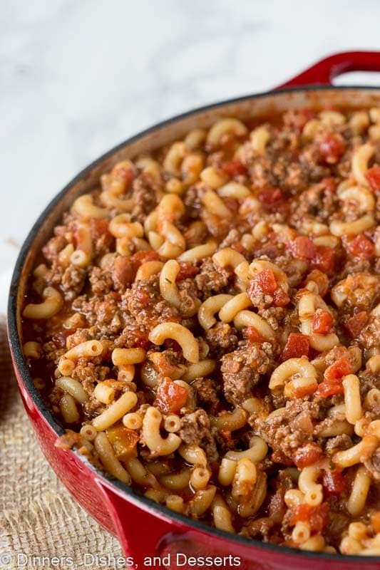 Close up of a red skillet filled with goulash made with macaroni.