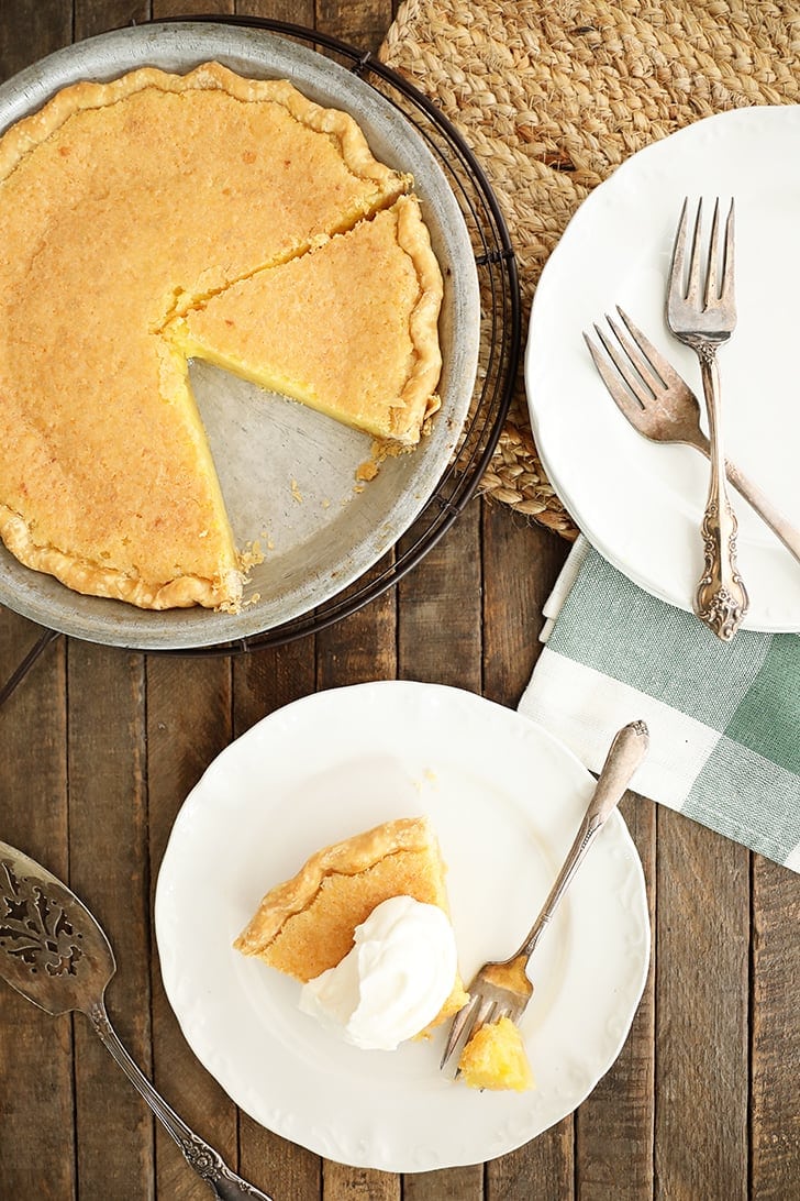 Overhead image of vinegar pie with a slice on a plate topped with cream.