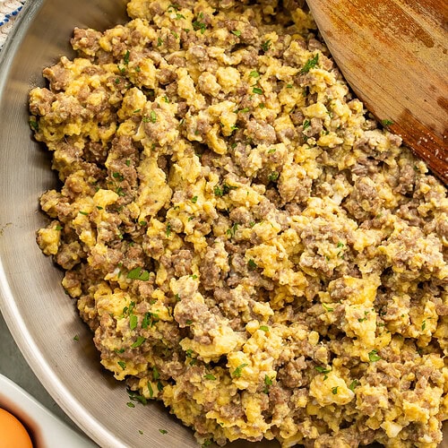 Skillet of ground beef and eggs topped with chopped parsley.