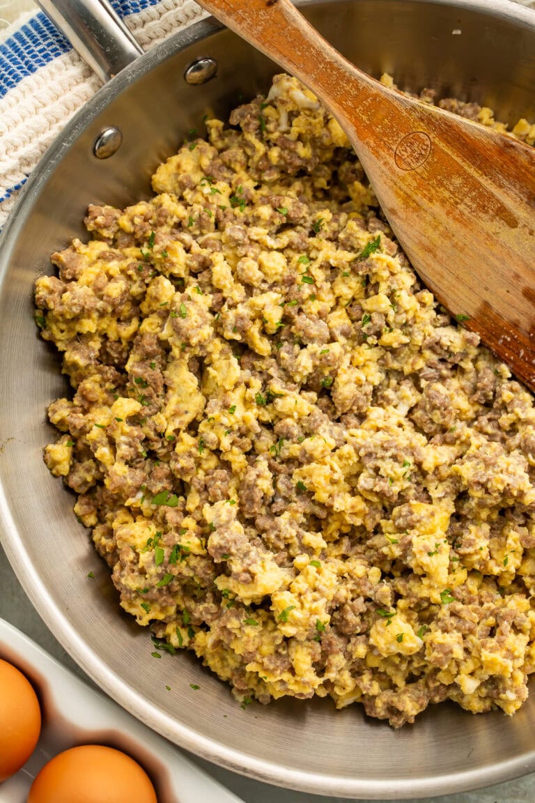 Skillet of ground beef and eggs topped with chopped parsley.