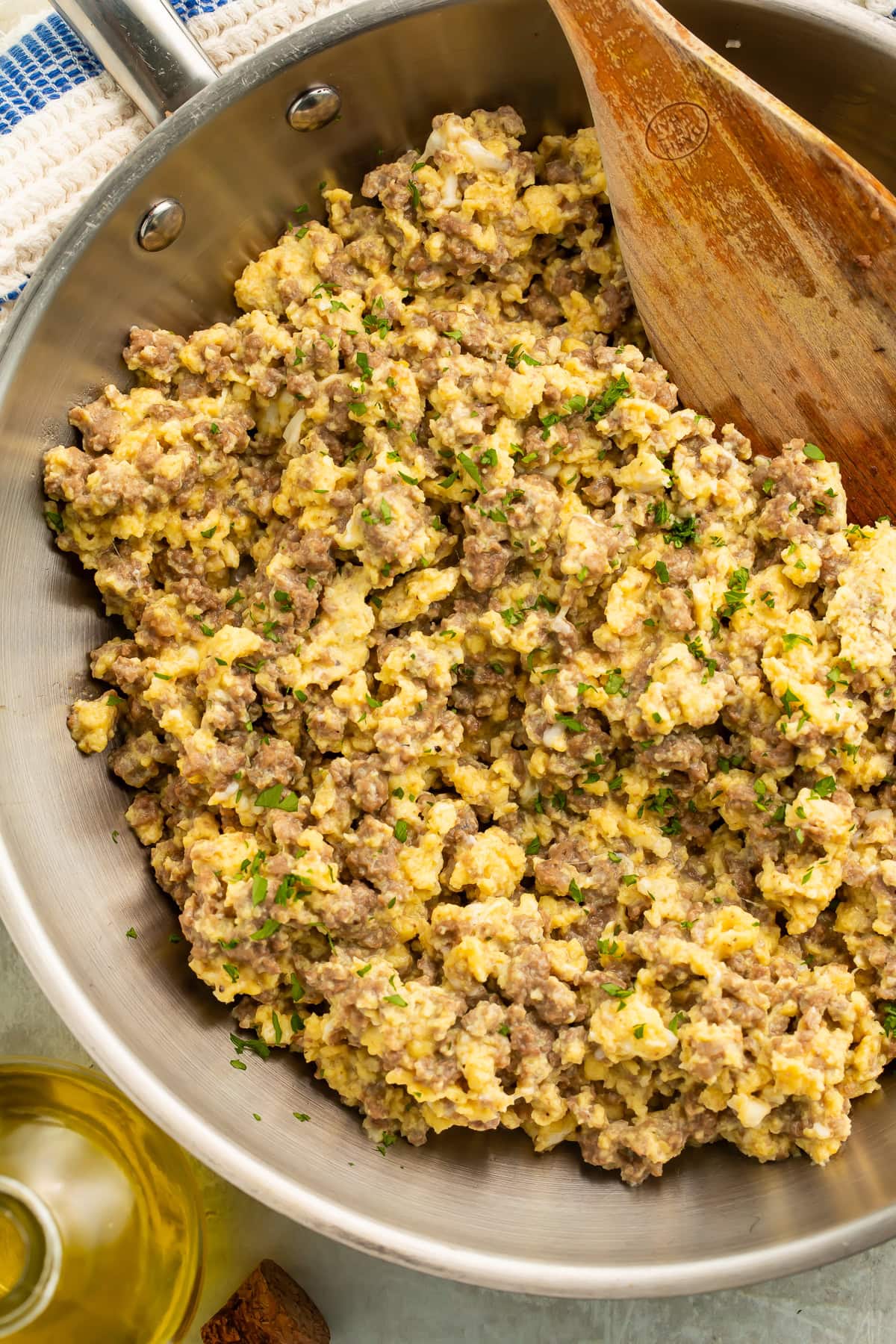 Close up of a pan of ground beef and eggs with a wooden spatula.