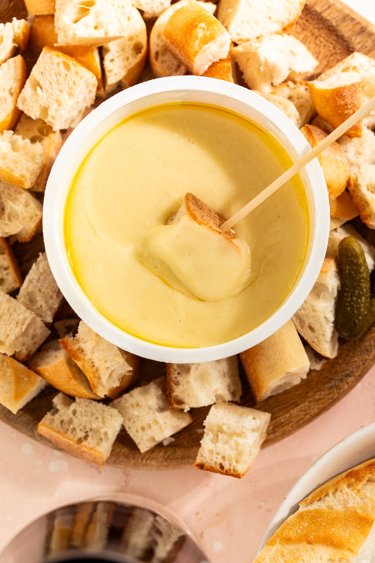Close up of a cheese fondu surrounded by cubes of French bread.