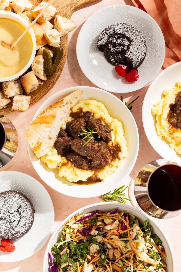 Overhead images of a Valentine's Day meal including braised short ribs with mashed potatoes, salad, fondu, and melt-in-the-middle chocolate puddings.